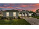 Charming gray home features well-manicured lawn, brick driveway, and beautiful dusk sky at 3176 Pearly Dr, Lakeland, FL 33812