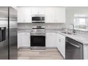 Modern kitchen with stainless steel appliances, granite countertops, and white cabinetry at 4486 Rapallo Ave, Winter Haven, FL 33884