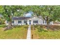 Beautiful single-story home with mature trees, a white exterior, blue shutters, and a well-kept lawn at 4825 Foxrun, Lakeland, FL 33813