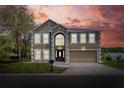 The house features a classic architecture, manicured lawn, and a two-car garage against a vibrant sky at 5163 Spanish Oaks Dr, Lakeland, FL 33805