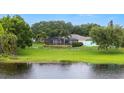 Expansive backyard with lush greenery, a serene lake view, and a screened-in lanai at 7016 Summit Cir, Winter Haven, FL 33884
