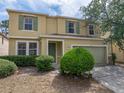Two-story home with green shutters and door, attached two-car garage, and mature front yard landscaping at 143 Alfani St, Davenport, FL 33896