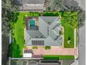 Aerial view of a beautifully landscaped home with a pool and solar panels on the roof at 148 Melissa Trl, Auburndale, FL 33823