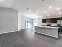 Open-concept living room with vaulted ceiling, lots of lighting, and dark gray wood flooring at 1851 Daystar Dr, Haines City, FL 33844