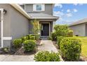 Inviting home entrance with a walkway flanked by manicured bushes and flowering plants at 2850 Sanderling St, Haines City, FL 33844