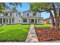 Inviting two-story home with a covered porch, lush green lawn, and mature trees at 727 S Missouri Ave, Lakeland, FL 33815