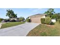 Driveway view of a house with a two-car garage, landscaped bushes, and green grass at 8904 Pebblebrooke Dr, Lakeland, FL 33810