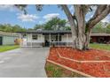 Charming one-story home with a welcoming porch and landscaped front yard featuring a beautiful mature shade tree at 113 Patrick Henry Rd, Bartow, FL 33830