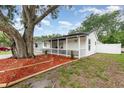 Charming one-story home with a covered porch, picket fence, and fresh landscaping featuring a large mature tree at 113 Patrick Henry Rd, Bartow, FL 33830