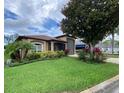 Beautifully landscaped front yard with lush green grass and mature trees surrounding a tan home at 1167 Motorcoach Dr, Polk City, FL 33868