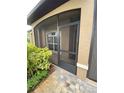 Close-up of the front porch with a screen door, stone walkway, and lush plantings at 1167 Motorcoach Dr, Polk City, FL 33868