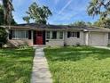 Inviting single-story home with a bright red door, neat landscaping, and an attached garage, creating great curb appeal at 1215 E Edgewood Dr, Lakeland, FL 33803