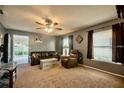 Cozy living room with plush carpeting, a ceiling fan, and two bright windows at 1410 Bramblewood Dr, Lakeland, FL 33811