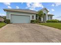 Spacious driveway leads to a home with a light blue exterior, accented by lush landscaping and an attached garage at 2593 Colonel Ford Dr, Lakeland, FL 33813