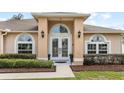 Close-up of a home's elegant double doors flanked by arched windows, enhanced by manicured landscaping at 3568 Jade Ln, Mulberry, FL 33860