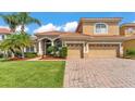Charming tan two-story home with a brick driveway, lush lawn, and well-maintained landscaping at 3980 Sunset Lake Dr, Lakeland, FL 33810