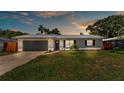 Charming single-story home at sunset featuring a new metal roof, gray garage door and beautiful landscaping at 416 Bayou Rd, Winter Haven, FL 33884