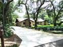 View of home with large driveway, mature trees, and nicely landscaped front yard at 5070 Ironwood Trl, Bartow, FL 33830