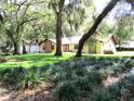 Home with stone accents surrounded by lush lawn and mature trees at 5070 Ironwood Trl, Bartow, FL 33830
