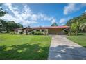 Single story home with a red metal roof, a long driveway, and a well-manicured lawn at 5140 Alderman Rd, Lakeland, FL 33810