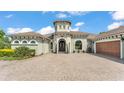 Beautiful home with tower detail, lovely front yard landscaping, and a brick driveway at 6475 Avalon Woods Dr, Lakeland, FL 33813