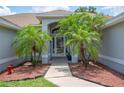 Inviting front entryway with arched entrance, tiled walkway, and tropical palm trees at 6789 Ashbury Dr, Lakeland, FL 33809