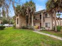Exterior of a two-story condo building featuring balconies, a stone facade, and lush green landscaping at 803 Orchid Springs Dr, Winter Haven, FL 33884