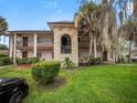 Two story condominium building with stone accents, green lawn, mature trees and black car in driveway at 803 Orchid Springs Dr, Winter Haven, FL 33884