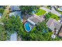 Aerial view of a home showcasing a screened-in pool, mature trees, and surrounding neighborhood at 111 Beverly Dr, Winter Haven, FL 33884