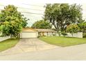 Charming single-story home with a well-manicured lawn, mature trees, and an attached one car garage at 111 Beverly Dr, Winter Haven, FL 33884