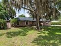 Well-kept brick home with a green lawn and a large, mature tree adding character at 1315 Costine Dr, Lakeland, FL 33809