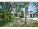 Inviting single-story home with mature trees, a well-manicured lawn, and tropical landscaping at 5 Pine Run, Haines City, FL 33844