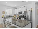 Modern kitchen with granite countertops, stainless steel appliances, white cabinetry, and a kitchen island at 546 Scott Lake Creek Ln, Lakeland, FL 33813