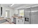 Well-lit kitchen featuring stainless steel appliances, granite countertops, and white cabinetry at 6 Rosewood Dr, Davenport, FL 33837