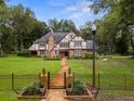 Charming Tudor-style home with a brick facade, black metal fence, and a stone pathway leading to the front door at 6001 Sweet Gum Run, Bartow, FL 33830