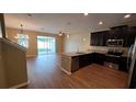 Open-concept living space with a kitchen island, dark cabinets, wood floors, and sliding doors to a screened patio at 6415 Torrington Cir, Lakeland, FL 33811