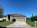Exterior elevation showcasing a well-kept lawn, driveway, and two-car garage at 8159 Woodvine Cir, Lakeland, FL 33810