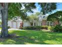 A well-maintained single-story home with a brick accents, mature trees, and lush green lawn at 1145 Denton St, Lakeland, FL 33803