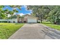 A long driveway leading to a home featuring a two-car garage and well-kept landscaping at 1910 Clubhouse Rd, Lakeland, FL 33813