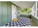 Cozy front porch featuring a checkered rug, white door, and screened windows, a perfect spot for relaxation at 2711 Crutchfield Rd, Lakeland, FL 33805