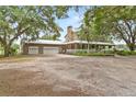Charming home features a wraparound porch, stone chimney, detached three-car garage and gravel driveway at 2911 Walker Rd, Lakeland, FL 33810