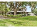 Beautiful front yard featuring green grass, mature trees, lush landscaping and a charming wraparound porch at 2911 Walker Rd, Lakeland, FL 33810