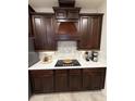 Elegant kitchen details include dark wood cabinetry, a stylish range hood, and sleek white countertops at 4124 Prima Lago Cir, Lakeland, FL 33810