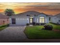 Charming one-story home with a well-manicured lawn and a paved driveway leading to a two-car garage at sunset at 5857 Macaw Pl, Lakeland, FL 33809