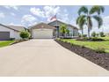 Inviting single-story home with a two-car garage, manicured lawn, and a decorative palm tree at 6001 Condor Dr, Lakeland, FL 33809