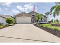 Inviting single-story home with a two-car garage, manicured lawn, and a decorative palm tree at 6001 Condor Dr, Lakeland, FL 33809