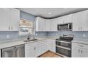 Bright kitchen featuring white cabinets, stainless appliances, and natural wood flooring at 619 Somerset Loop, Auburndale, FL 33823