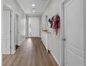 Well-lit hallway featuring hardwood floors, neutral paint, and a glimpse of the front door at 647 Chicago Way, Dundee, FL 33838