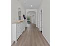 Bright hallway featuring hardwood floors, white trim, and an open view into the dining area at 647 Chicago Way, Dundee, FL 33838