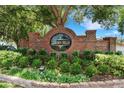 Welcoming entrance to Garden Hills featuring a brick sign with lush greenery and landscaping at 7642 Habersham Dr, Lakeland, FL 33810